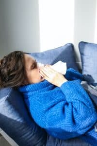Mujer resfriada limpiándose la nariz
