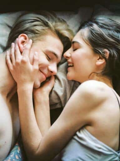 Pareja eterosexual recostados en una cama vestidos semidesnudos