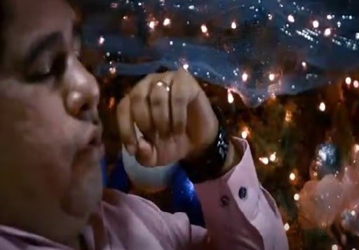 Se ve la imagen de la cabeza de un hombre de talla grande y su cara de perfil y detrás de él las luces de un árbol de navidad